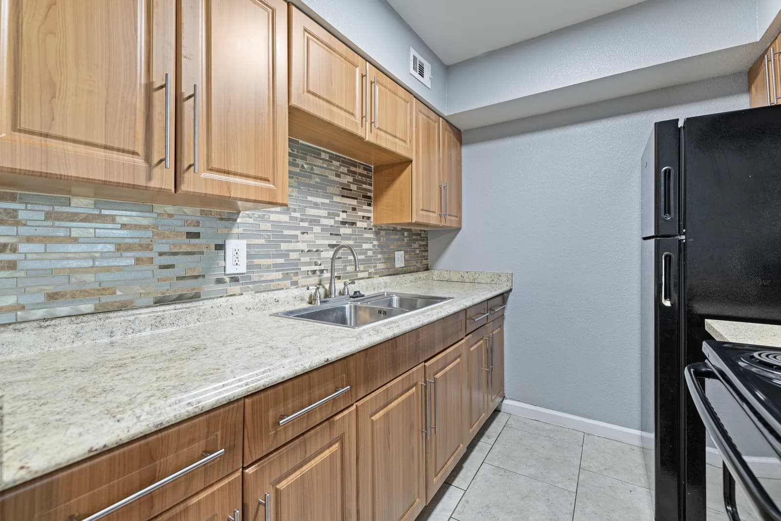 Close view of Waverly kitchen counter, backsplash, cabinetry and sink